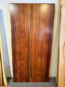 A close-up of an African Mahogany solid wood slab, displaying its rich reddish-brown color, fine grain patterns, and smooth, polished surface. The natural wood texture is highlighted, showcasing the slab’s unique, elegant appearance with subtle variations in color and grain.