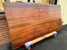 A close-up of an African Mahogany solid wood slab, displaying its rich reddish-brown color, fine grain patterns, and smooth, polished surface. The natural wood texture is highlighted, showcasing the slab’s unique, elegant appearance with subtle variations in color and grain.