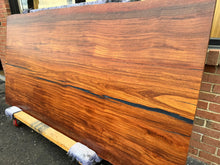 A close-up of an African Mahogany solid wood slab, displaying its rich reddish-brown color, fine grain patterns, and smooth, polished surface. The natural wood texture is highlighted, showcasing the slab’s unique, elegant appearance with subtle variations in color and grain.