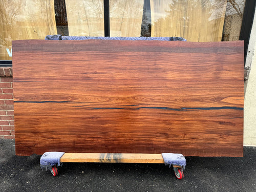 A close-up of an African Mahogany solid wood slab, displaying its rich reddish-brown color, fine grain patterns, and smooth, polished surface. The natural wood texture is highlighted, showcasing the slab’s unique, elegant appearance with subtle variations in color and grain.